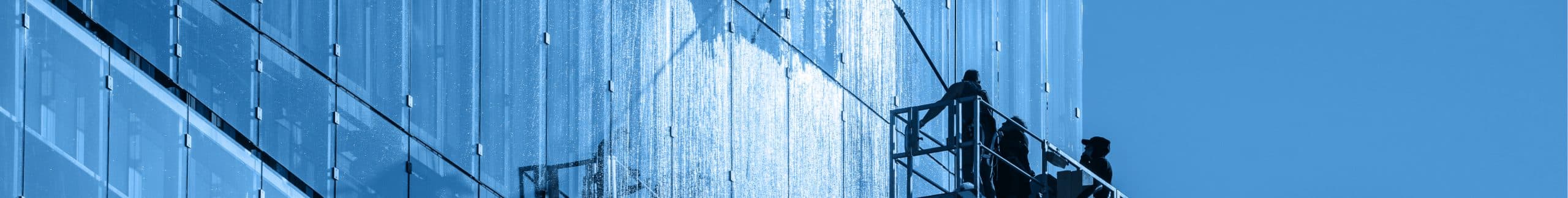 Glazenwassers op een hoogwerker reinigen een glazen gevel